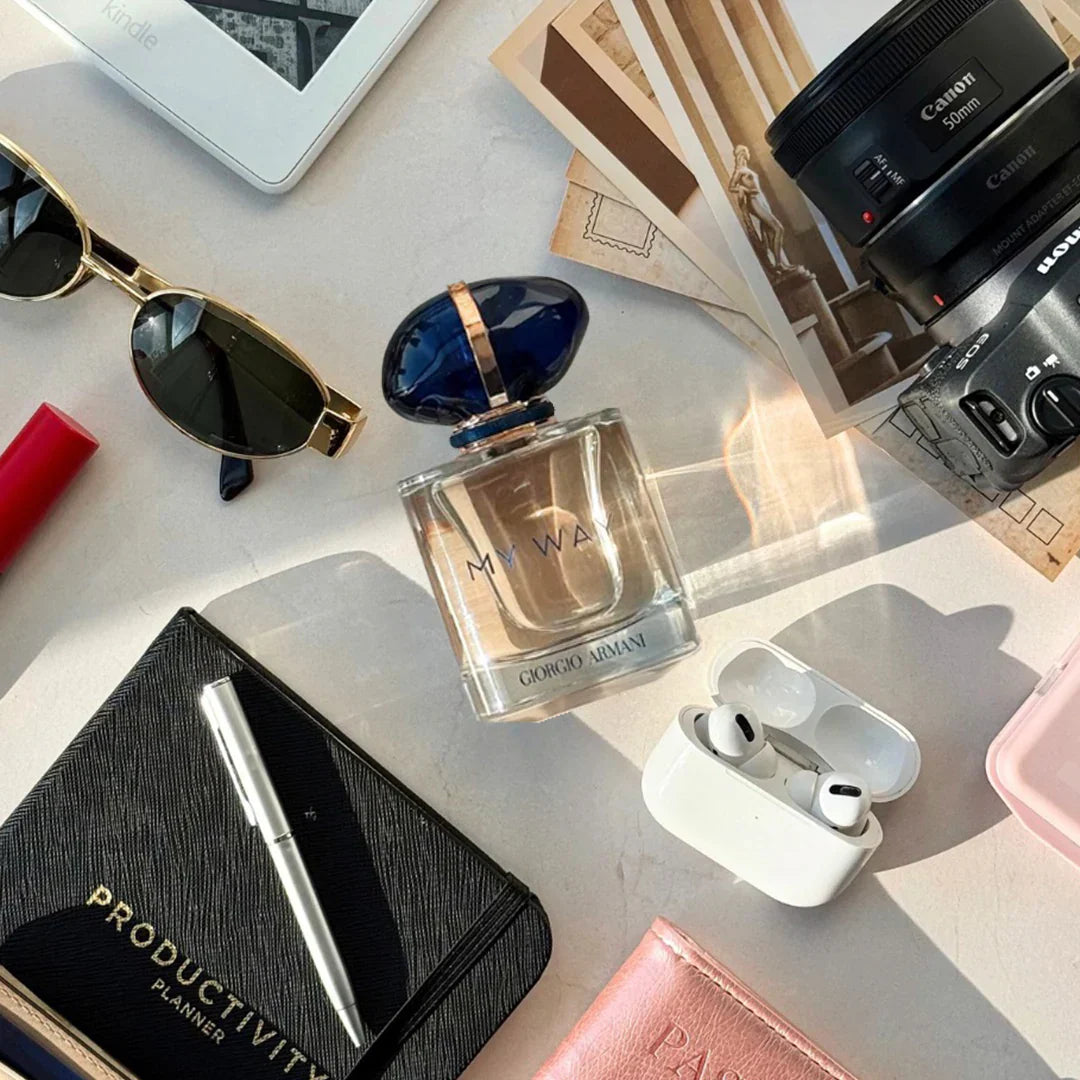 Perfume bottle, sunglasses, camera, and other items on a light surface